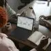 Three people in a meeting at a table discussing schedule on their Microsoft laptop